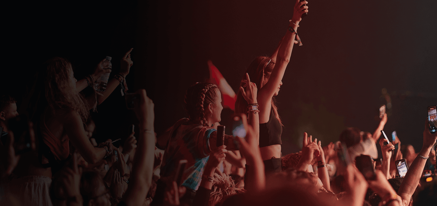 Energetic festival crowd cheering with hands up at a live music concert stage